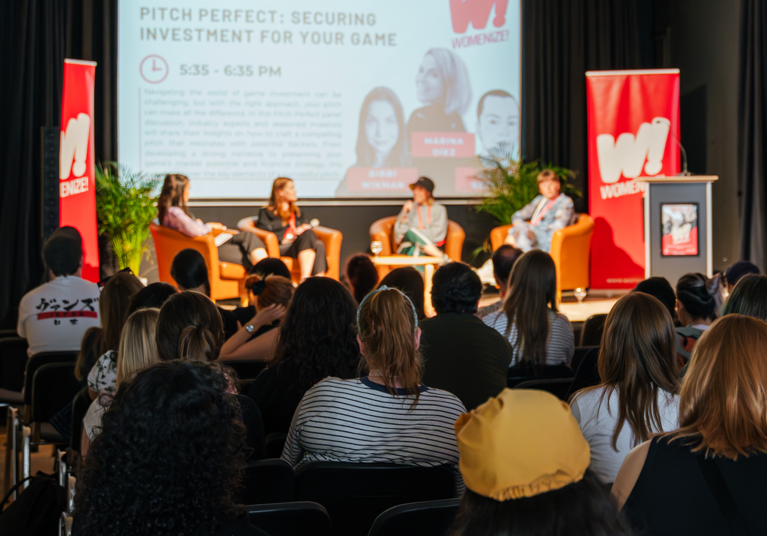 conference Panelists on stage and audience at a Womenize! event